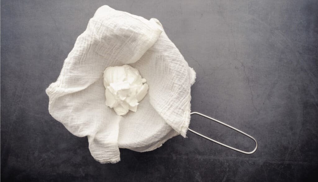 Kokosjoghurt, das auf einem Tuch in einem Sieb abtropft und zu Kokos-Quark wird.