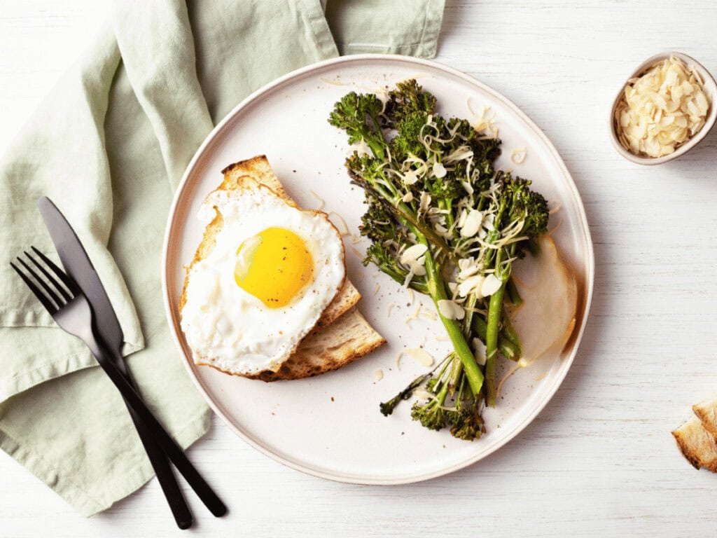 Broccolini aus der regionalen Biokiste gegart auf einem Teller mit einem Stück Hirsebrot mit Spiegelei.