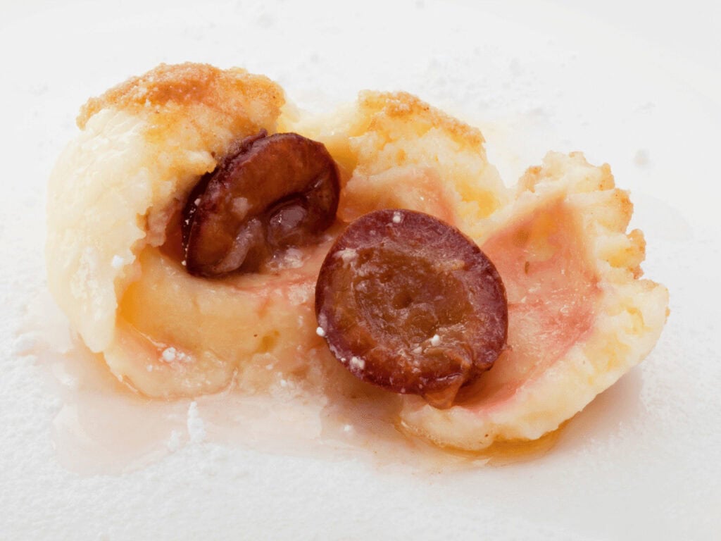 Geöffnete Zwetschgenknödel, bei dem man die Frucht sieht.