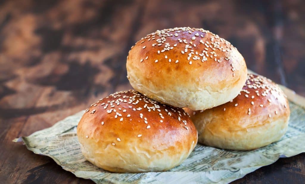 Drei glutenfreie Burger Buns auf einem beigen Tuch.