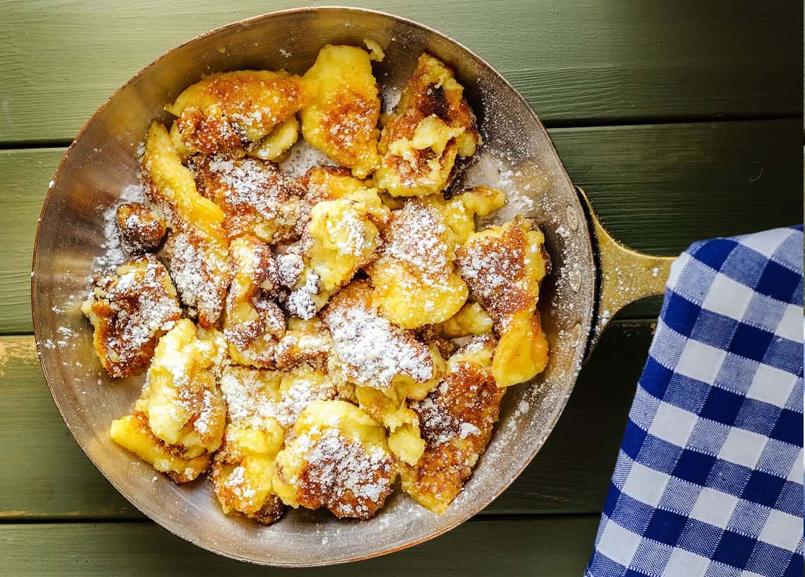 Kaiserschmarrn in einer Metallpfanne mit kariertem Küchentuch