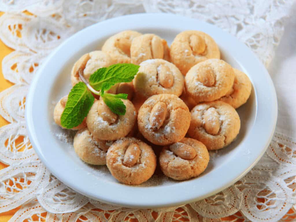 Glutenfreie Mandelmakronen auf einem weißen Teller, getoppf mit Minze.