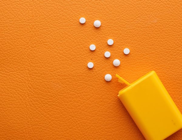 Süßstoffdose mit kleinen Tablettchen auf orangem Hintergrund, zum Thema: Süßstoffe treiben den Blutzucker hoch.