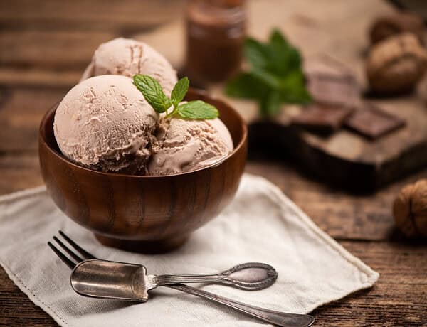 Drei Kugeln histaminarmes, veganes Mandeleis in einer braunen Holzschale.