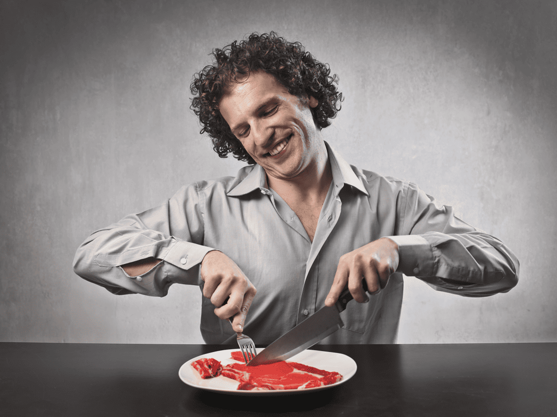 Mann isst rohes rotes Fleisch, zum Thema: Rotes Fleisch ist ungesund.