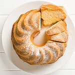 Glutenfreier, histaminarmer Gâteau de Savoie auf einem weißen Teller, ein Stück liegt auf der Seite.